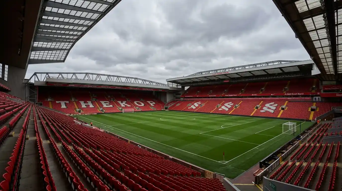 Estadio de fútbol Anfield con césped verde y gradas vacías bajo cielo nublado